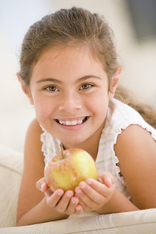 Young girl eating apple in living room smiling