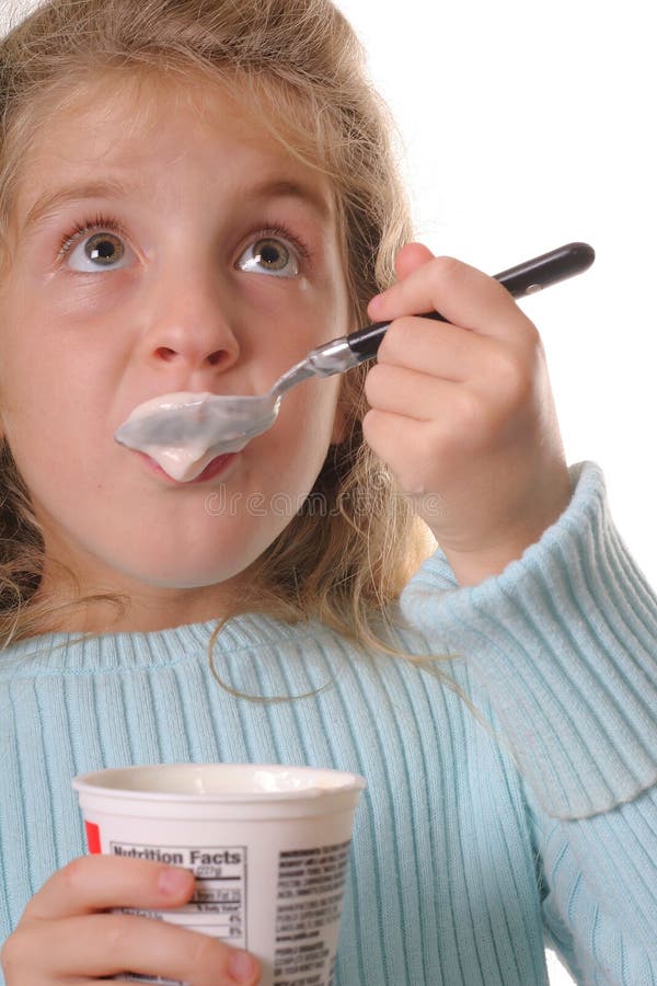 Young girl eating yogurt vertical looking up