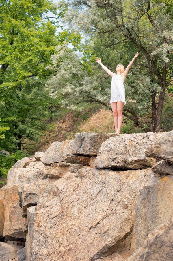 Young girl enjoys nice weather at the edge of a cliff, with her