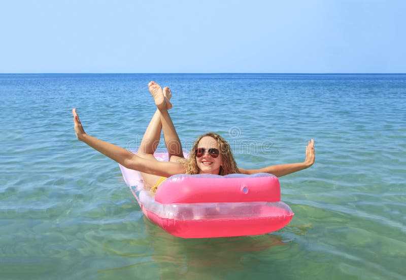 Young girl floating on a mattress in the sea