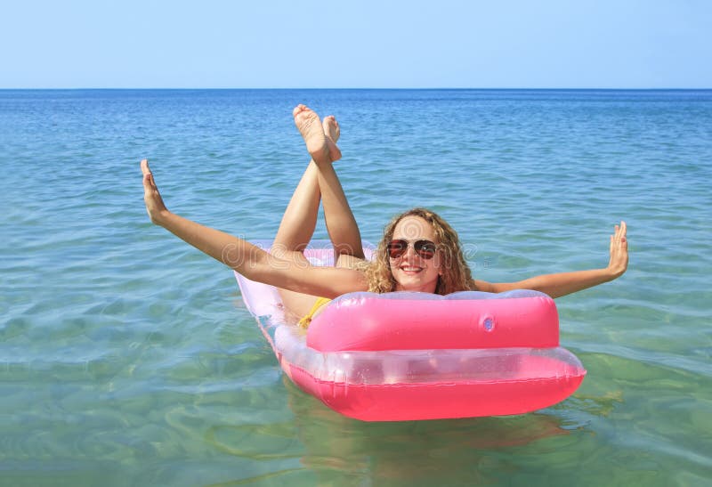 Young girl floating on a mattress in the sea