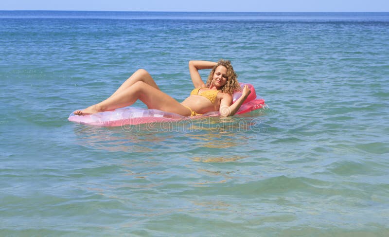 Young girl floating on a mattress in the sea