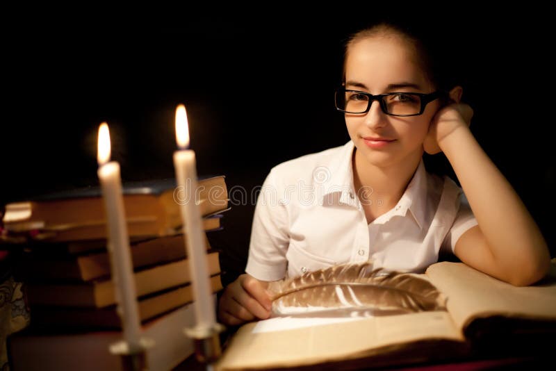 Young girl in glasses over book in dark