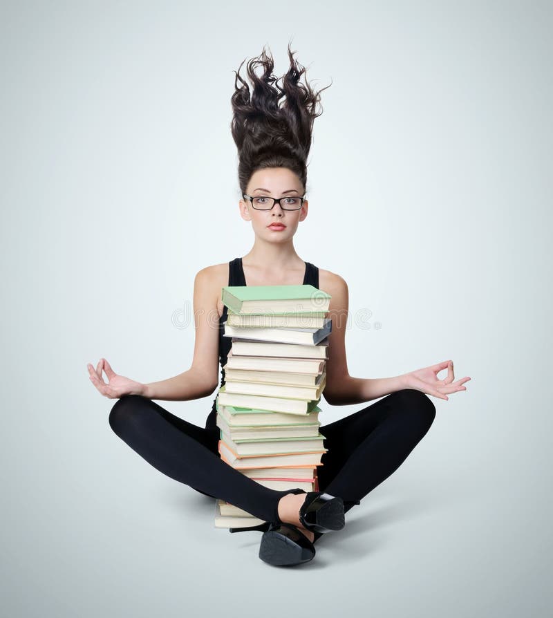 Young girl in glasses with a pile of books in the lotus position royalty free stock photo Young girl in glasses with a pile of books in the lotus position royalty free stock photo