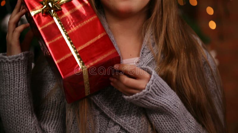 Young girl grabbing a christmas present lifting it to her face, laughing