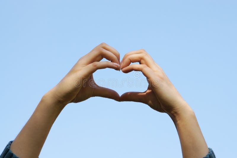 Young girl hands holding hands in heart shape with the clear blue sky background stock photos