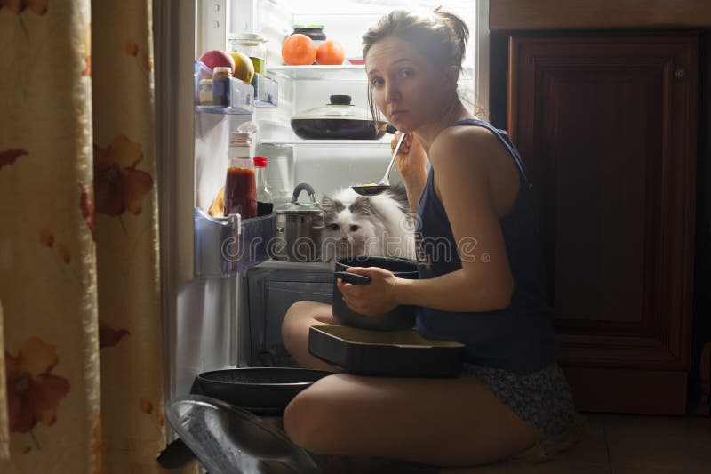 Young girl and her fluffy cat eating at night.