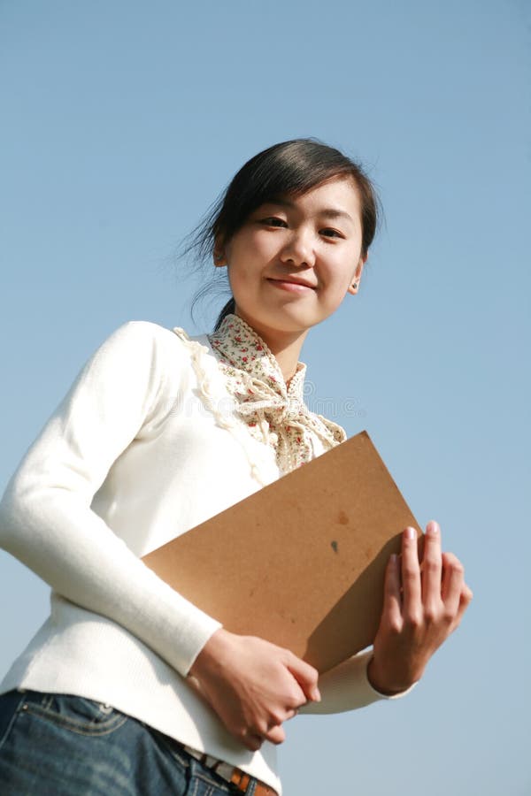 Young girl holding books with blue sky