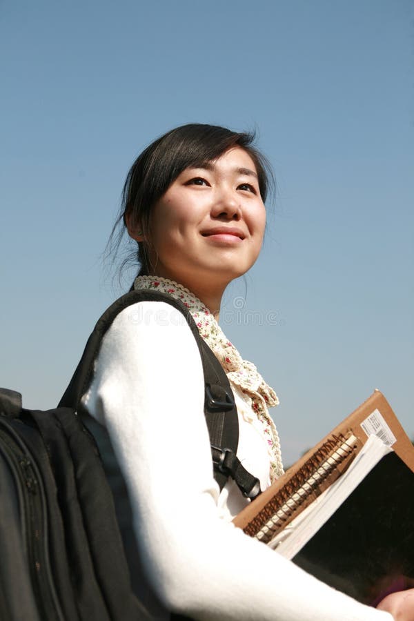 Young girl holding books with blue sky