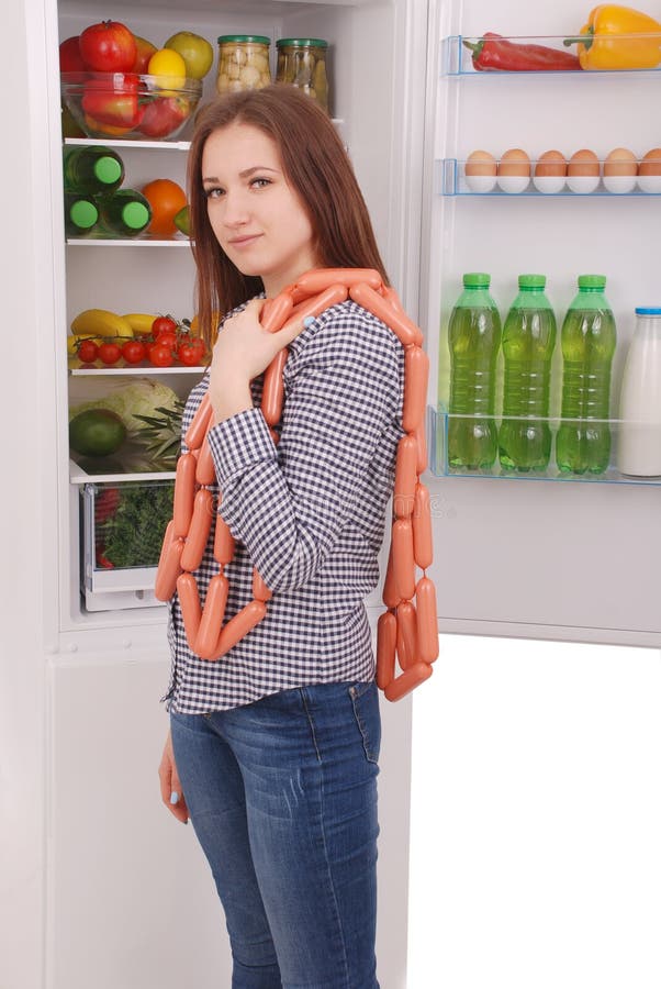 Young girl holds sausages on the refrigerator background royalty free stock images Young girl holds sausages on the refrigerator background royalty free stock images