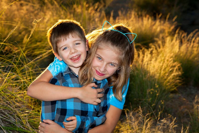Young Girl Hugs Her Younger Brother From Behind For a Portrait i stock photos Young Girl Hugs Her Younger Brother From Behind For a Portrait i stock photos