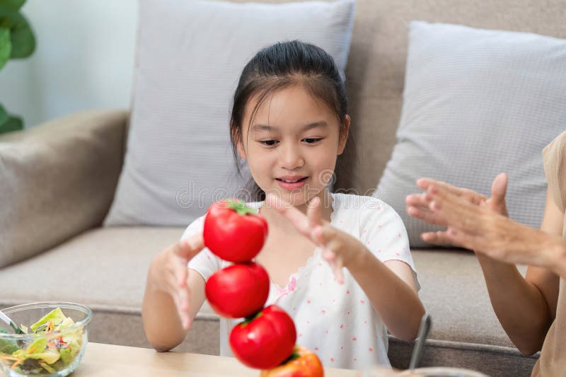 Wellness through healthy eating: Young girl stacking fresh tomatoes stock photos