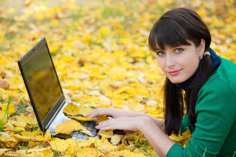 Young girl with a laptop in a autumn foliage