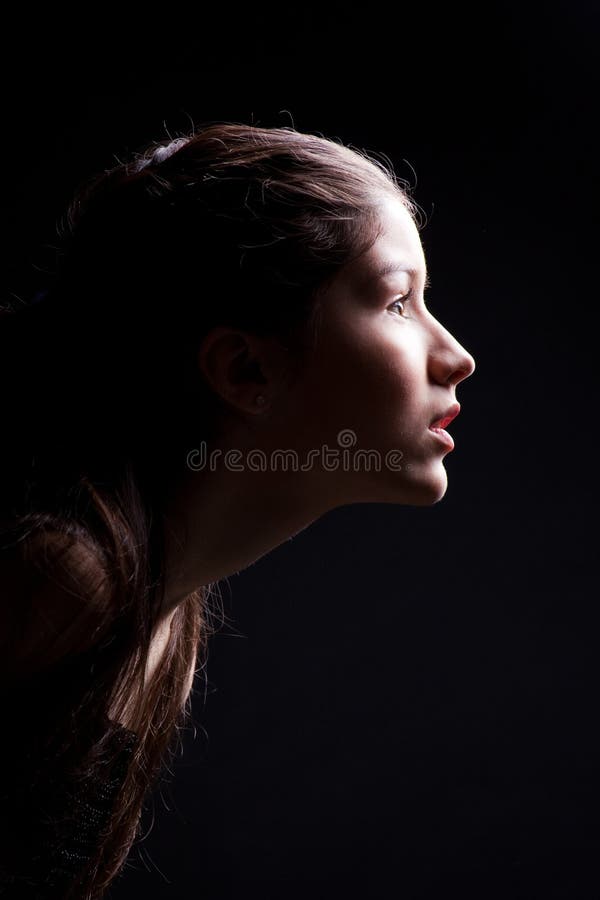 Young girl lasting forward to light on black