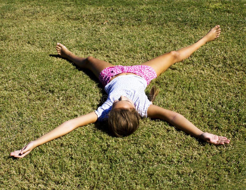 A Young Girl Lies on the Mown Grass Stretching Her Arms and Legs Stock ...