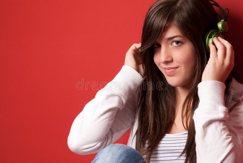 Young girl listening music with headphones on red