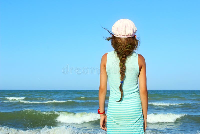 Young Girl Looking On A Calm Sea And Blue Skies, Back View.