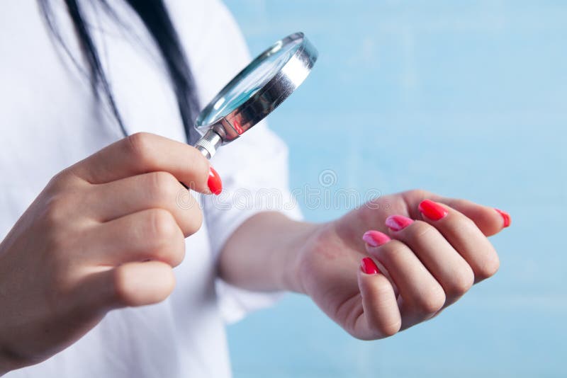 Young Girl Looks at Painted Nails with a Magnifying Glass Stock Image