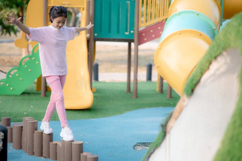 A young girl is playing in a park with a slide and a swing royalty free stock photography