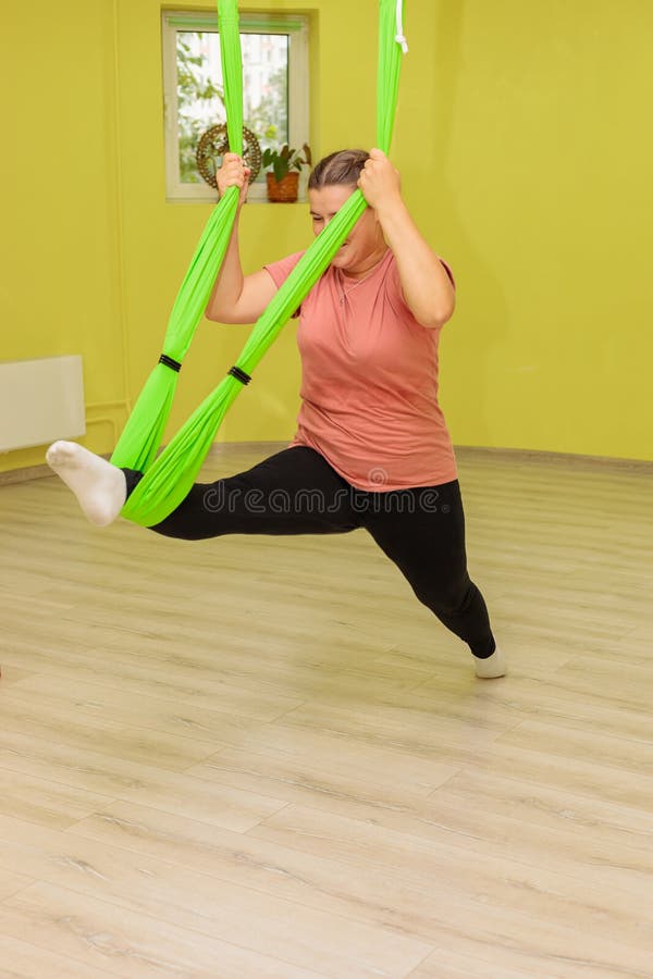 A Young Girl Practices Yoga on a Hammock in the Hall. Stock Image