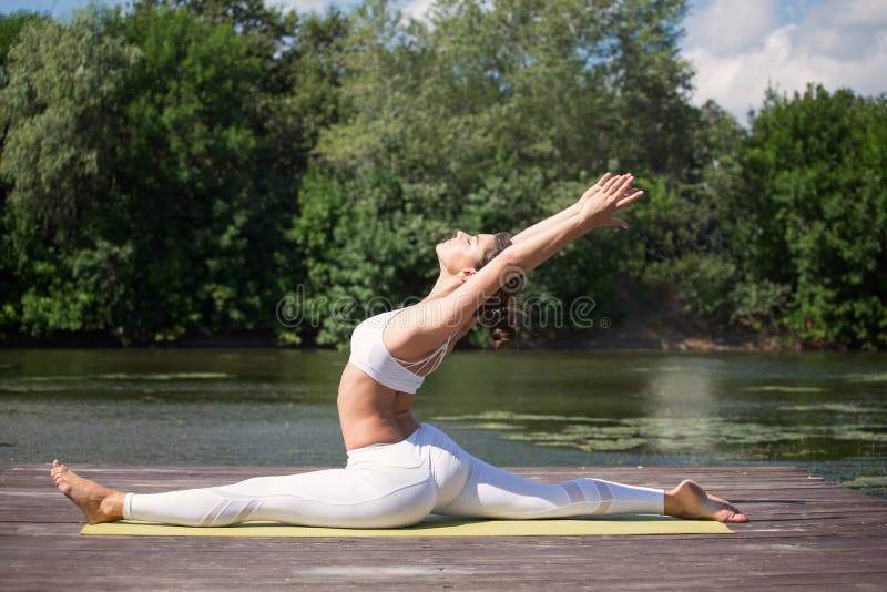 Young girl practices yoga on the shore of the lake, the concept of enjoying privacy and concentration, sunlight