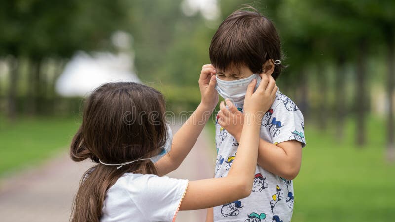 A young girl helps her brother to wear a face mask from the coronavirus covid19