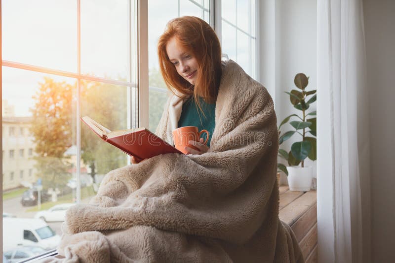 Young girl reading book and drinking morning coffee at home