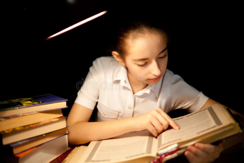 Young girl reading book at night dark at library