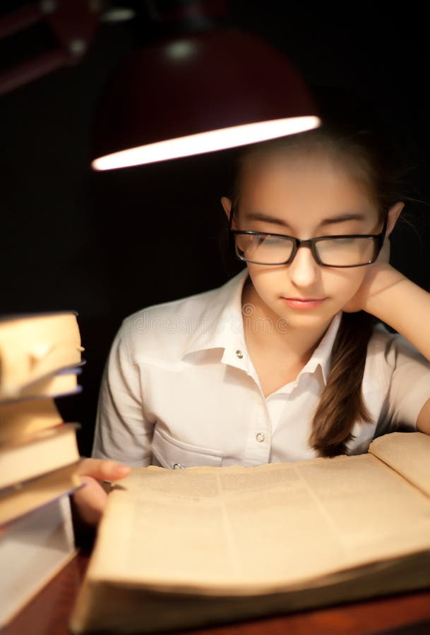 Young girl reading book under lamp