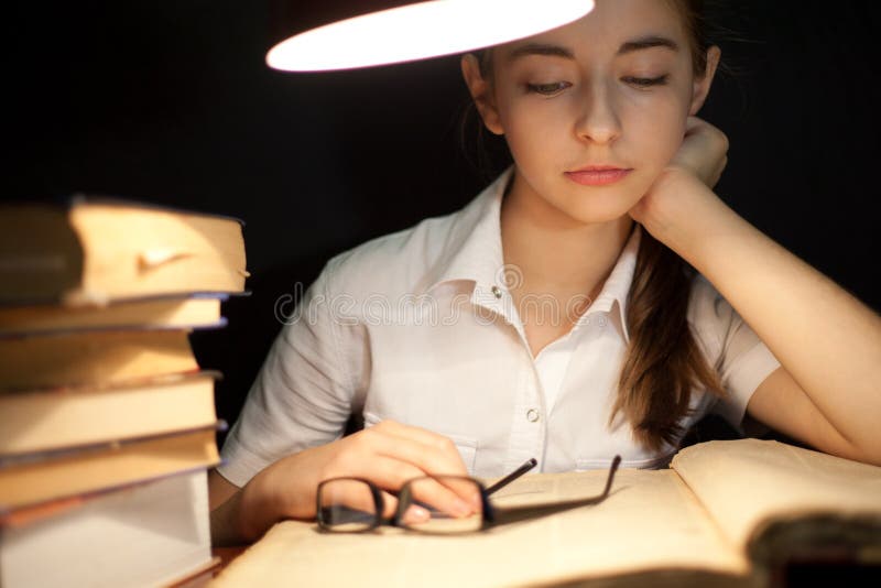 Young girl reading book under lamp