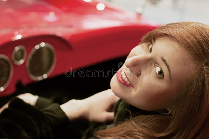 Young girl with red hair sits in a red car with an open top and look into the camera stock photography Young girl with red hair sits in a red car with an open top and look into the camera stock photography