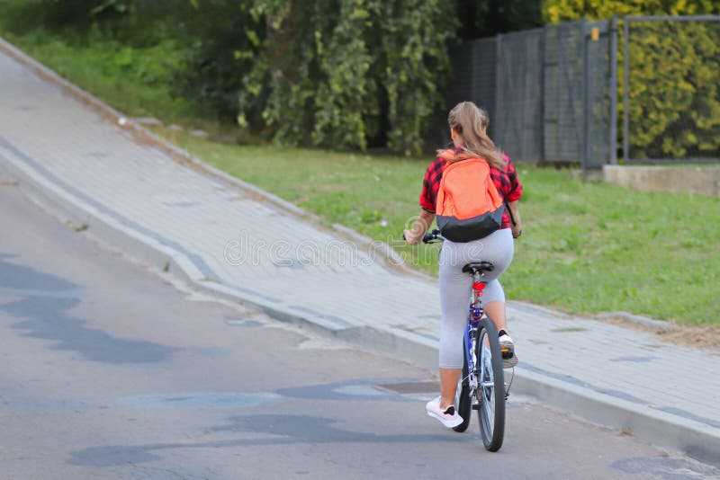 A young girl rides a bicycle on the road by the road sign of danger and speed limits of up to 40 km/h. Active way of life of young people. Ecological mode of transport is popular in the city