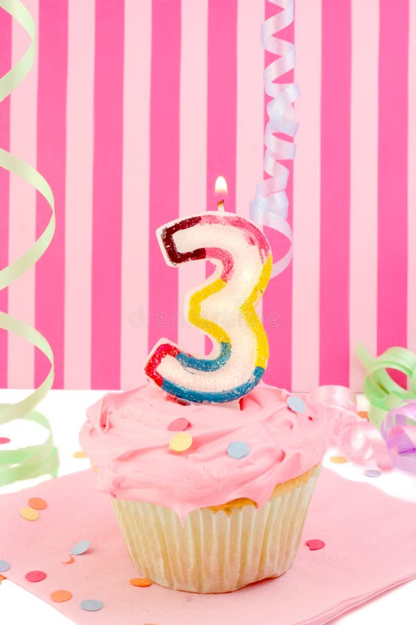 Young girl's birthday. Birthday cupcake with pink frosting and and decorative background celebrating child's third anniversary royalty free stock images Young girl's birthday. Birthday cupcake with pink frosting and and decorative background celebrating child's third anniversary royalty free stock images