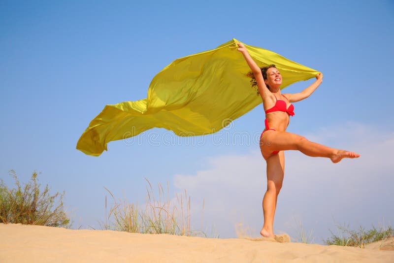 Young girl on sand with yellow shawl in hands