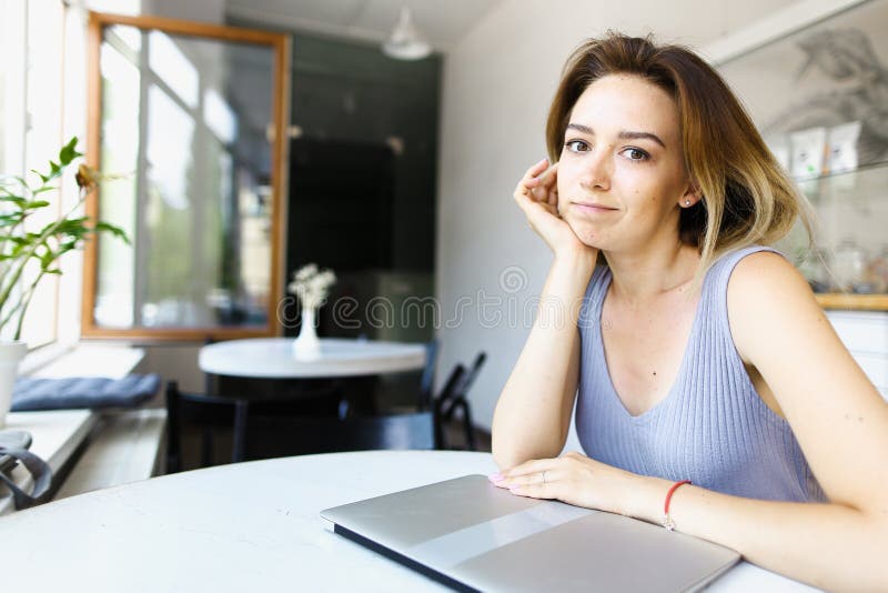 Young girl sitting at cafe with closed laptop.
