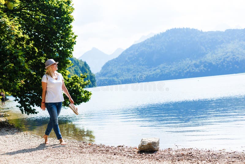 Young girl sitting near by beautiful lake . Original wallpaper from summer morning