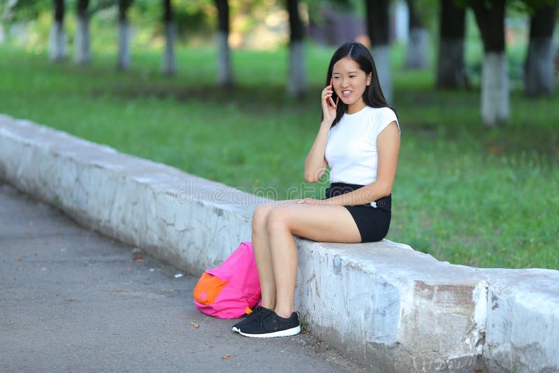 Young girl sitting and talking on the phone in the park