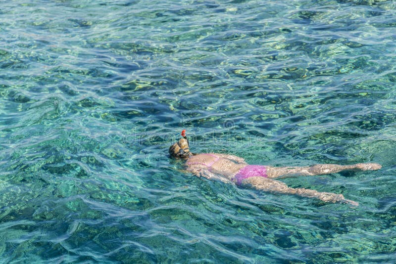 Young girl snorkeling in tropical water on vacation. Woman swimming in blue sea. Snorkeling girl in full-face snorkeling mask stock photography Young girl snorkeling in tropical water on vacation. Woman swimming in blue sea. Snorkeling girl in full-face snorkeling mask stock photography