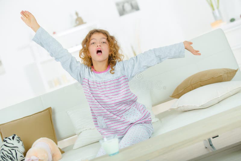 Young girl on sofa stretching and yawning royalty free stock photo
