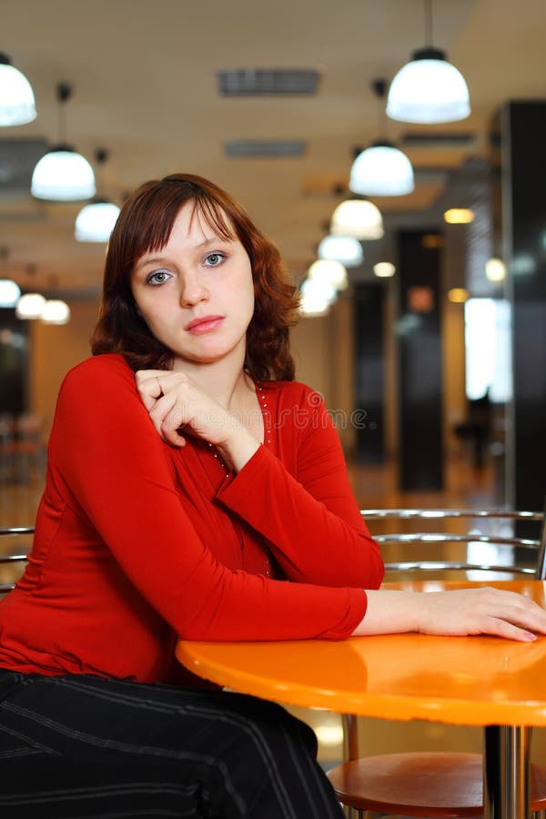 Young girl sorrowful sitting in empty cafe