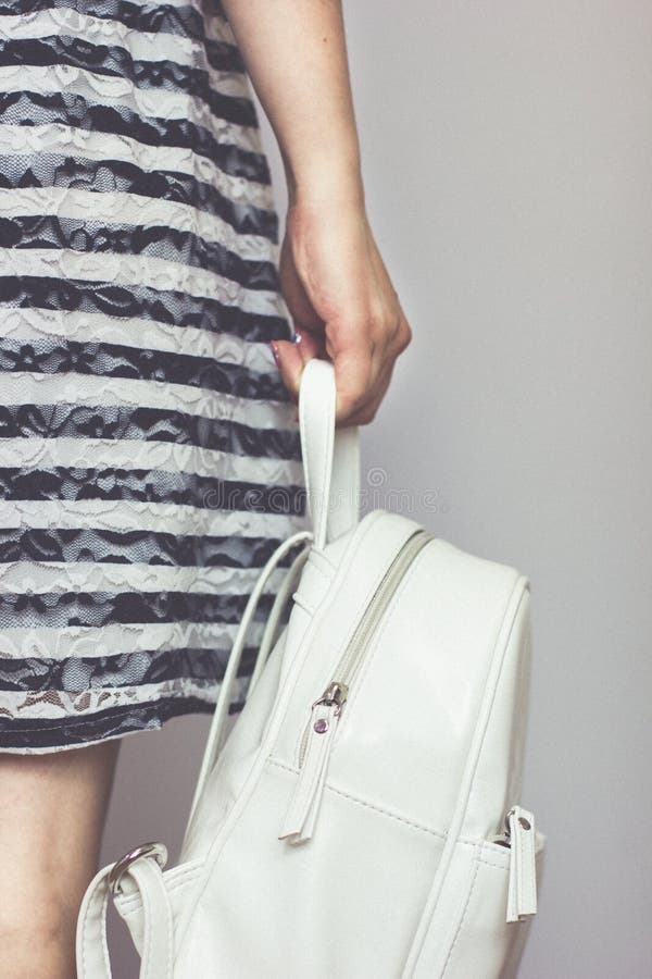 Young Girl in a Striped Dress is Holding a White Backpack. Stock