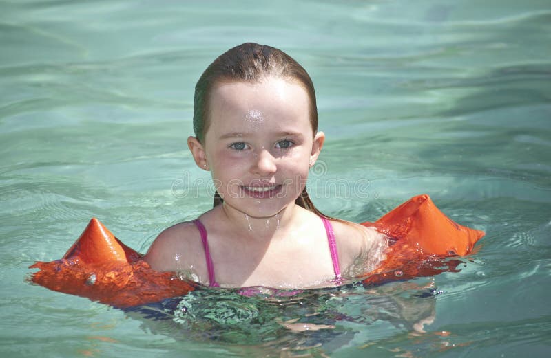 Beautiful young girl swimming in a pool in the heat of the summer.