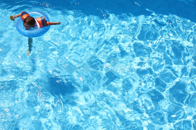 Young girl swimming with arm bands and a ring in a pool all on her own