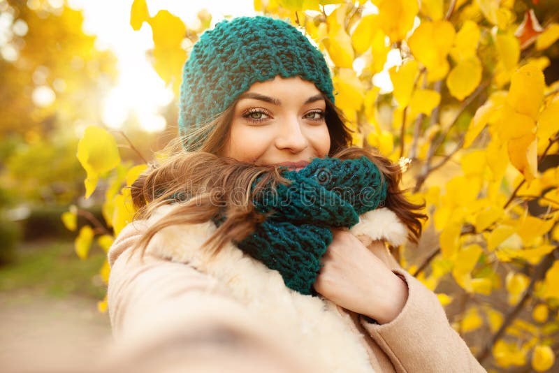 Young girl takes a selfie on the backgroung autumn beautiful leaves. Autumn concept. Videobloger