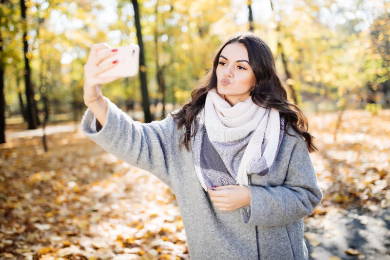 Young girl takes a selfie on the backgroung of a wall with autumn beautiful leaves. Young girl takes a selfie on the backgroung of a wall with autumn beautiful leaves.