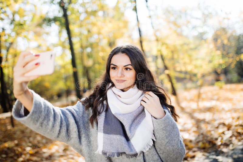 Young girl takes a selfie on the backgroung of a wall with autumn beautiful leaves. Young girl takes a selfie on the backgroung of a wall with autumn beautiful leaves.