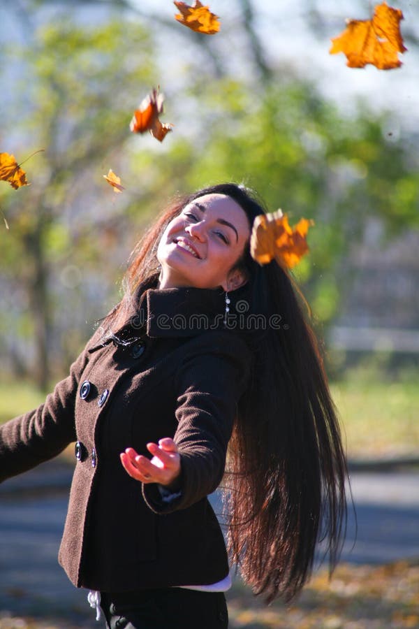 Young girl throwing autumn leaves