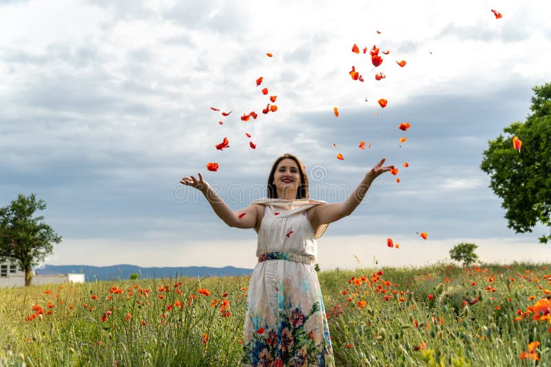 Are you picking flowers at the moment. Young woman picking Poppies Flowers Walking in Summer field enjoying Landscape.