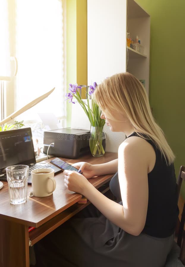 Young girl using smartphone and computer at home