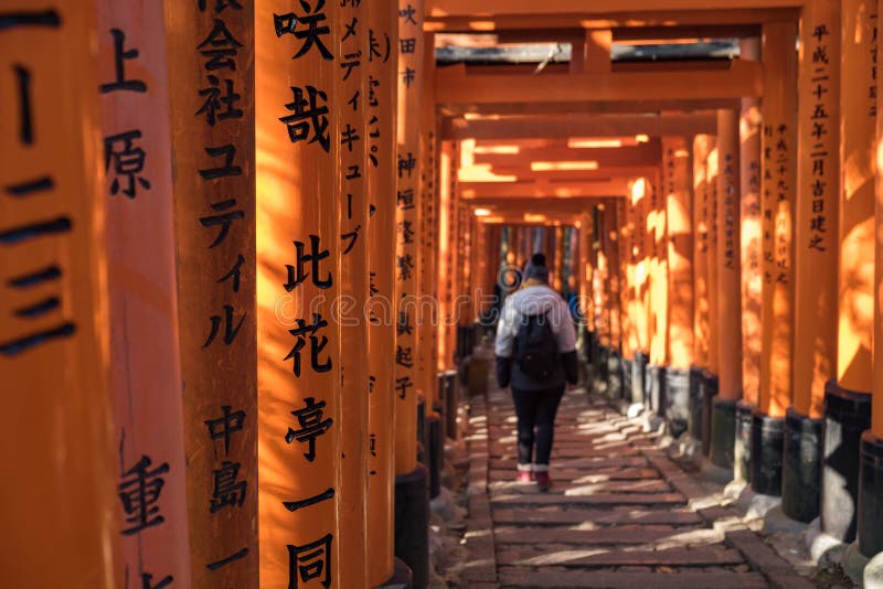 Young girl walking down a path full of red wooden toriis with black inscriptions in Fushimi Inari Shri stock photos Young girl walking down a path full of red wooden toriis with black inscriptions in Fushimi Inari Shri stock photos